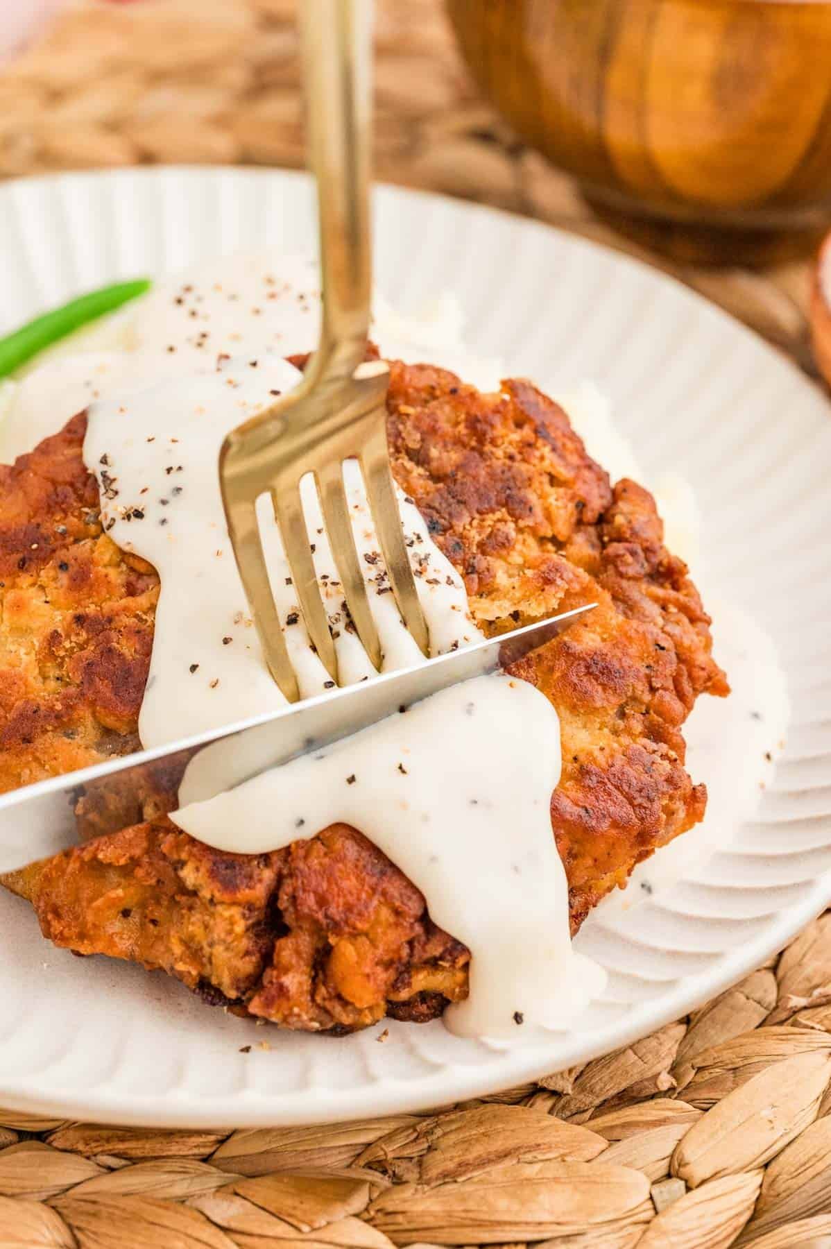 Cutting into chicken fried steak with a fork and knife.