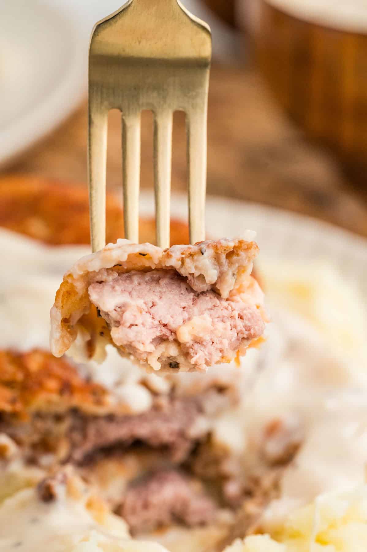 Close-up of a bite of chicken fried steak on a fork.