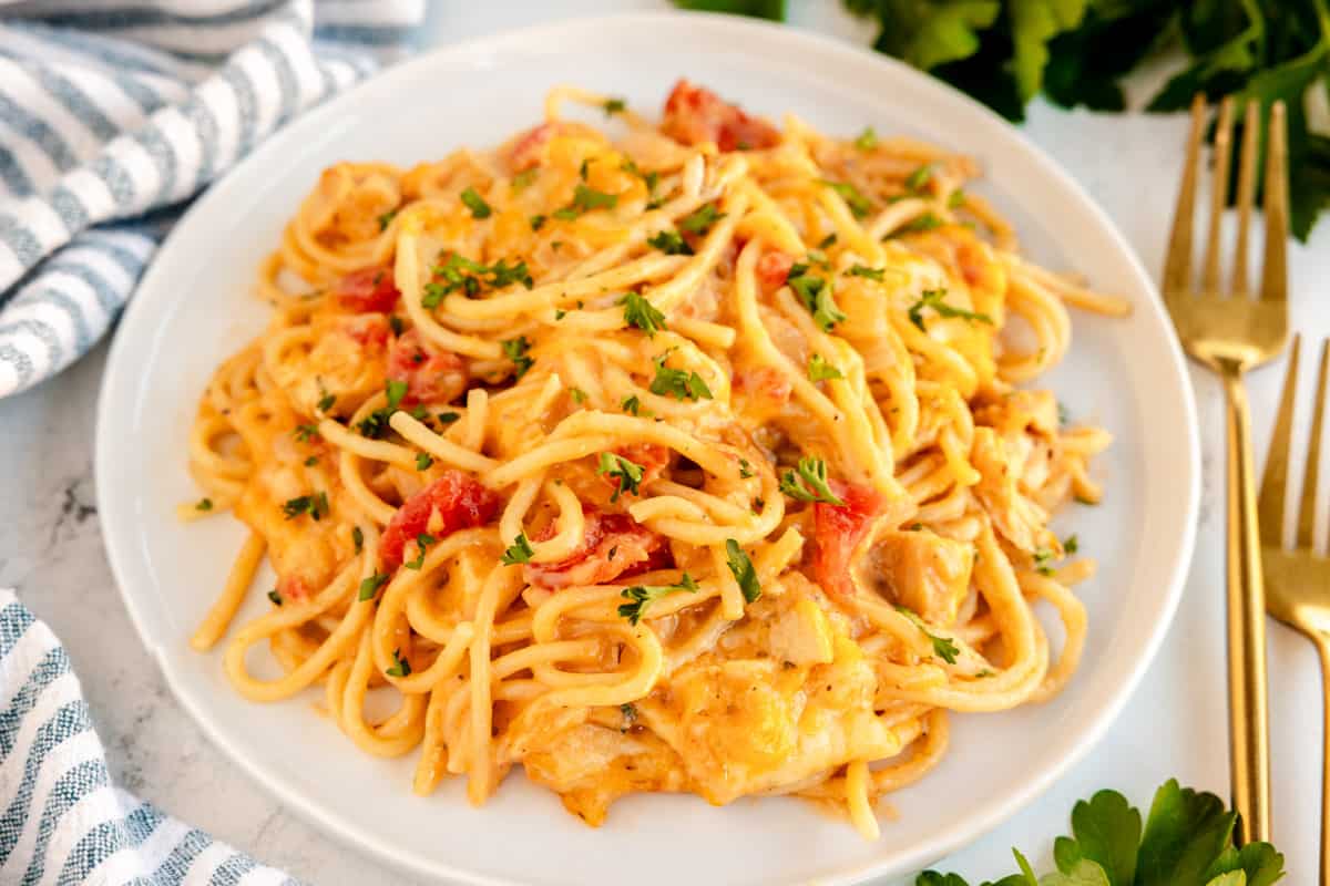 chicken spaghetti on a white plate with a napkin and silverware.