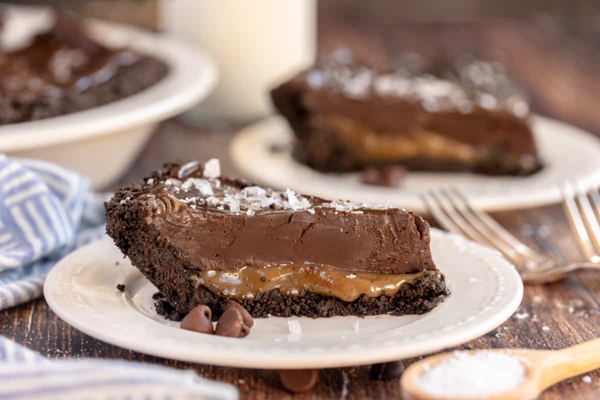 slice of chocolate tart on a white plate with a blue napkin.