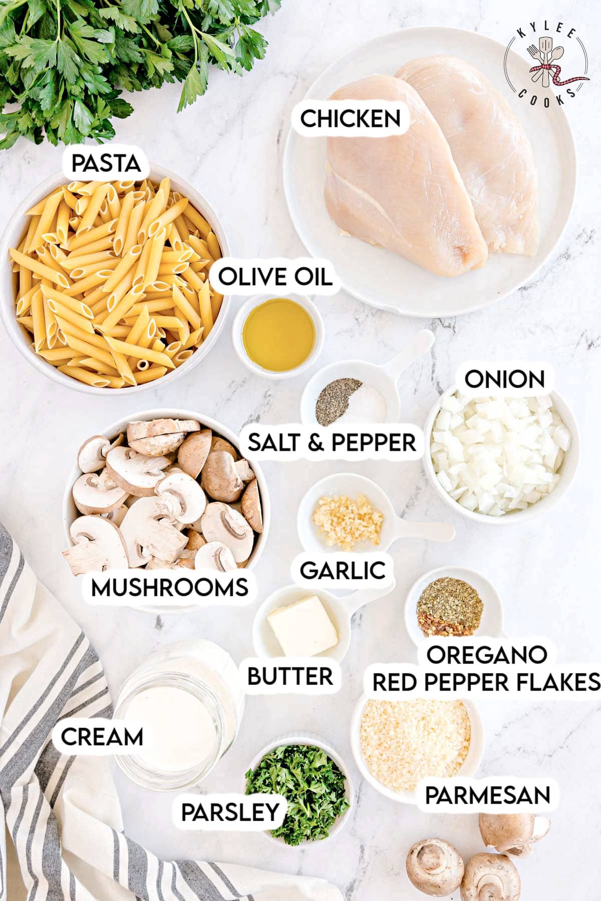 Raw ingredients in bowls for creamy chicken mushroom pasta. Text on the image says 'PASTA, CHICKEN, OLIVE OIL, SALT & PEPPER, ONION, MUSHROOMS, GARLIC, BUTTER, OREGANO, RED PEPPER FLAKES, CREAM, PARMESAN, PARSLEY'.