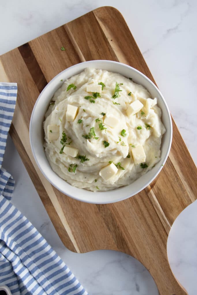 mashed potatoes in a white bowl on a wooden board