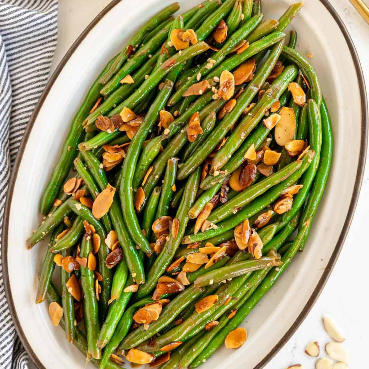 A plate of green beans topped with toasted almonds.