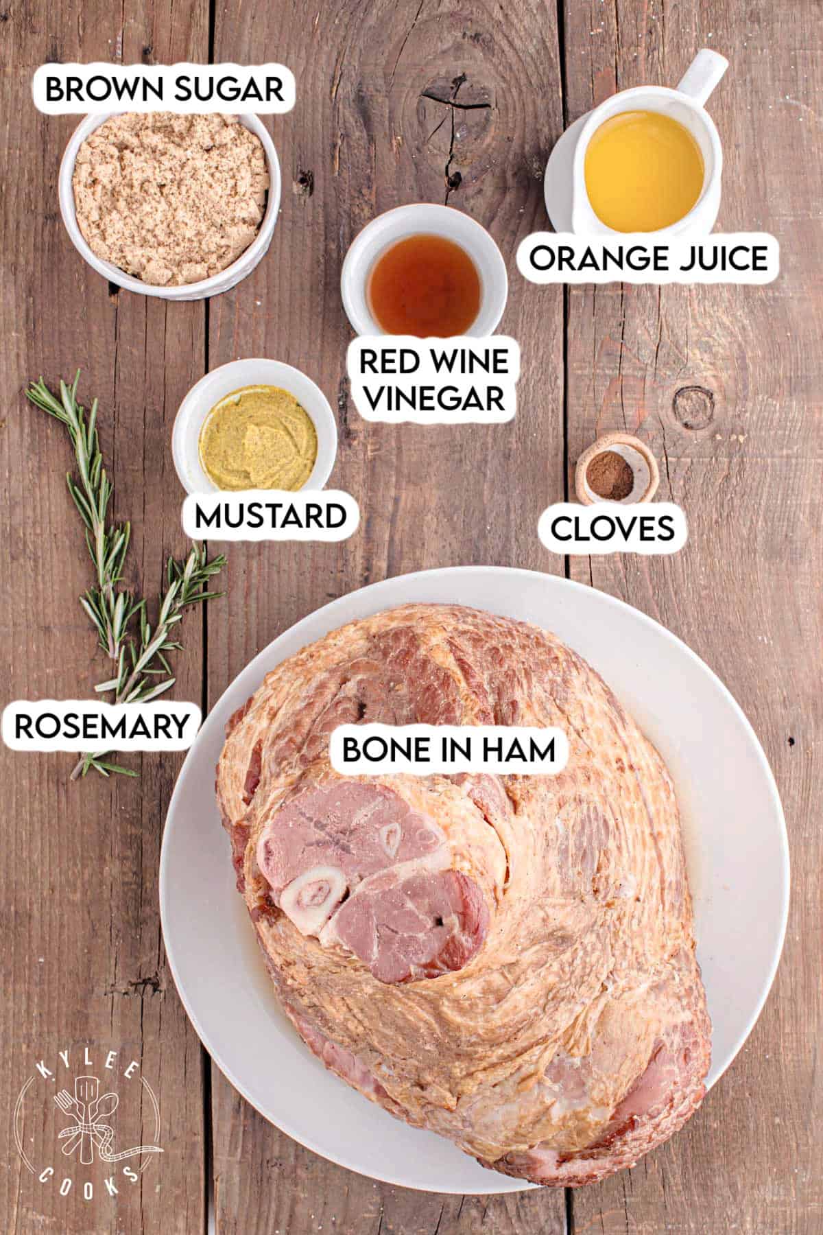 Ingredients for the glazed ham arranged on a table, labeled: brown sugar, orange juice, mustard, red wine vinegar, cloves, etc.