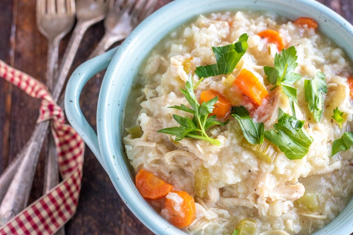 chicken and rice in a teal bowl with silverware wrapped in a gingham ribbon