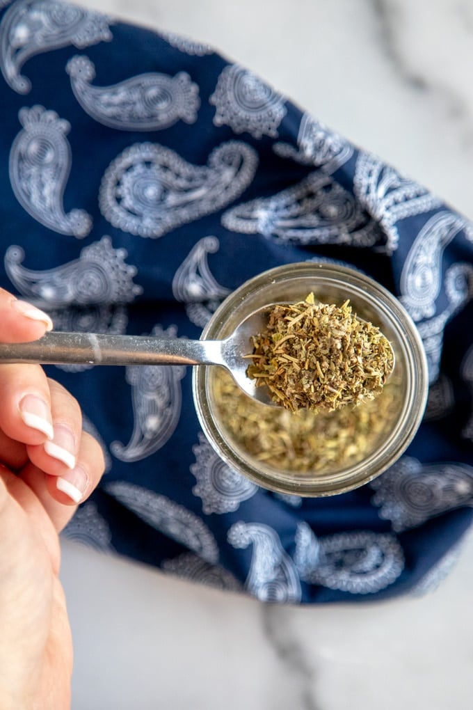 italian seasoning in a jar, with a blue napkin and a spoon