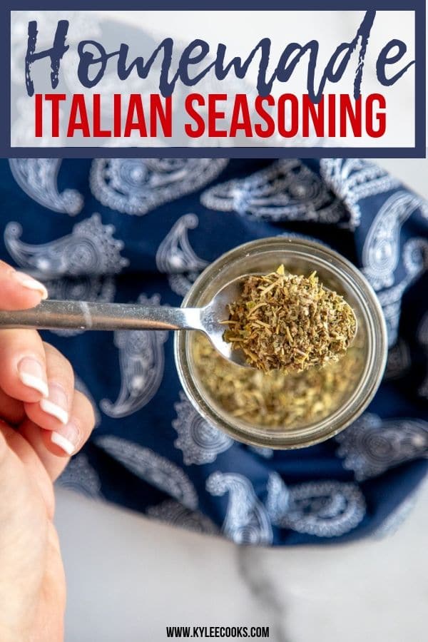 a hand holding a spoon of italian seasoning above a jar.