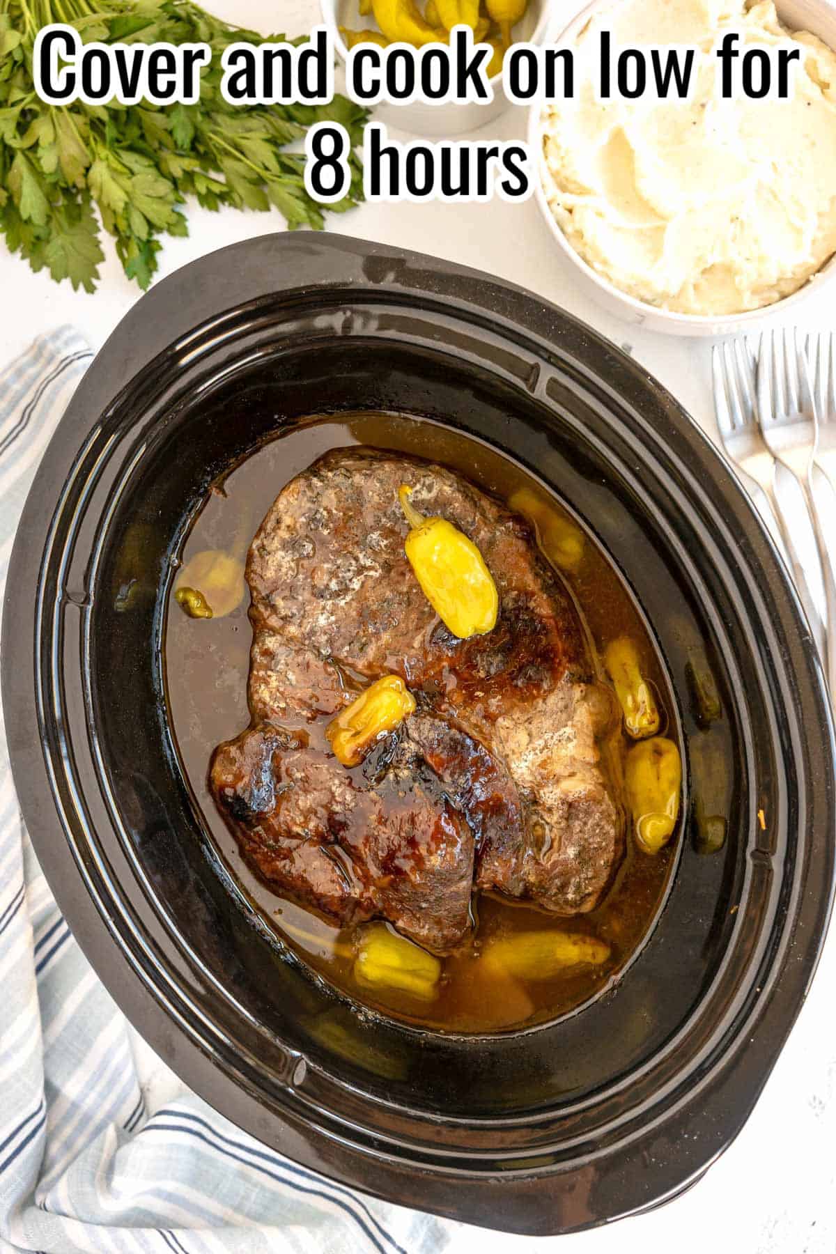 A cooked Mississippi pot roast in a black crockpot.