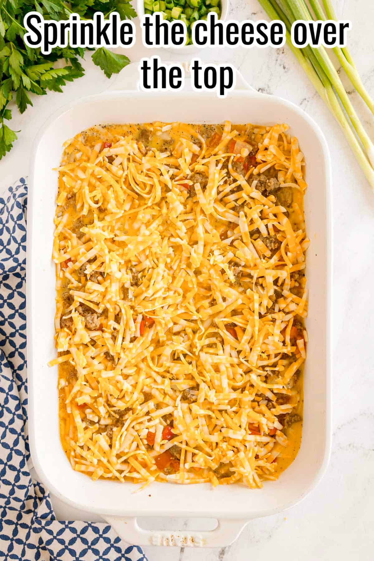Shredded cheese sprinkled over the unbaked casserole. Text on the image says 'Sprinkle the cheese over the top'.