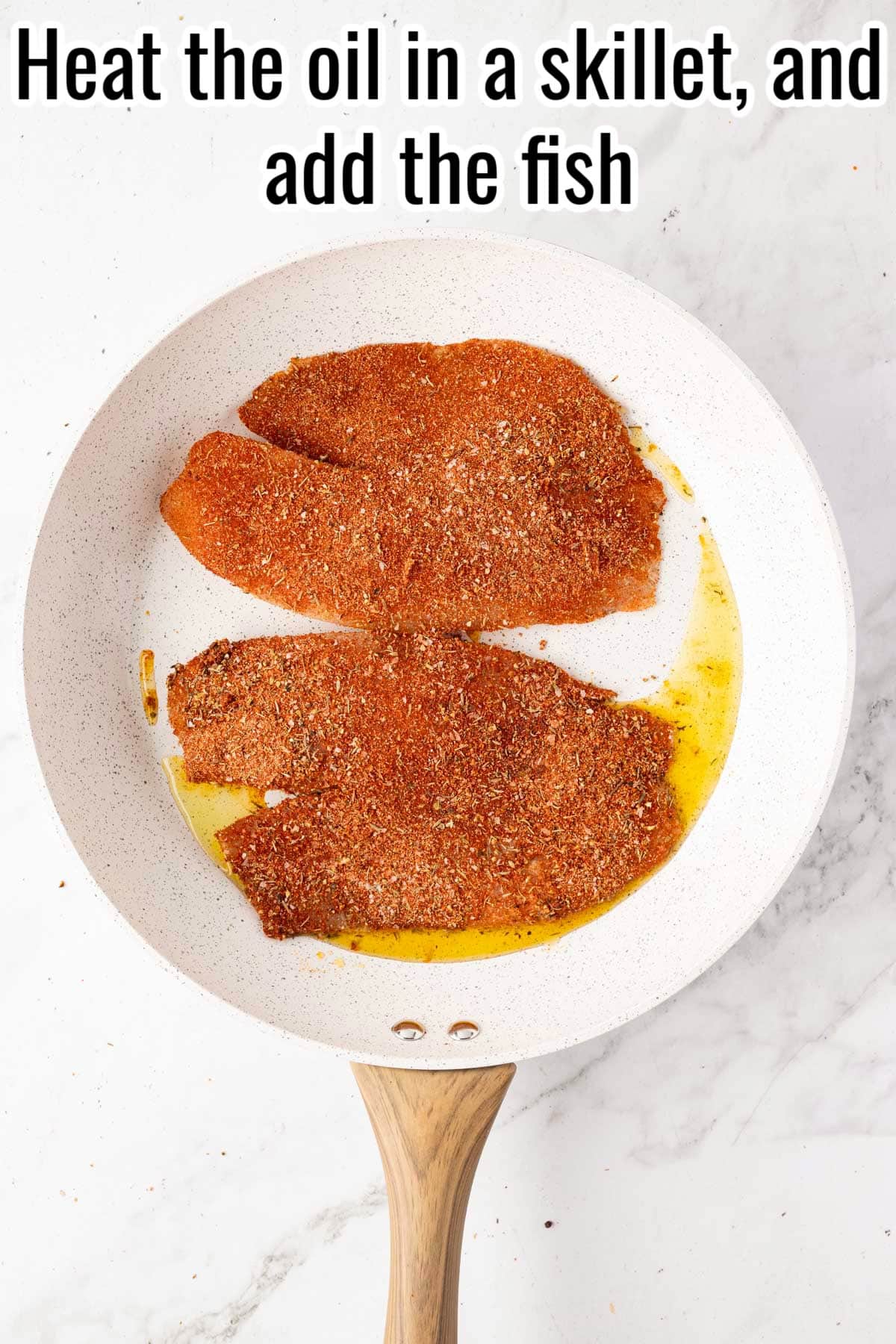 Seasoned tilapia fillets in a skillet with oil. Text on the image says 'Heat the oil in a skillet, and add the fish'.