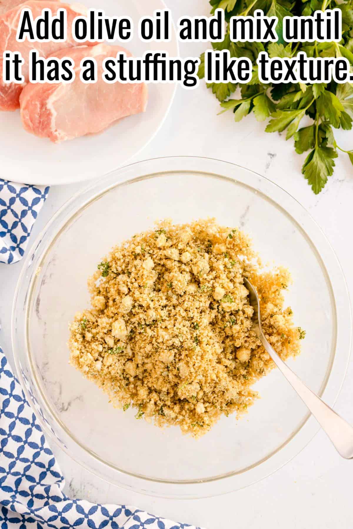 A bowl of seasoned breadcrumb mixture with a spoon. Text on the image says 'Add olive oil and mix until it has a stuffing like texture'.