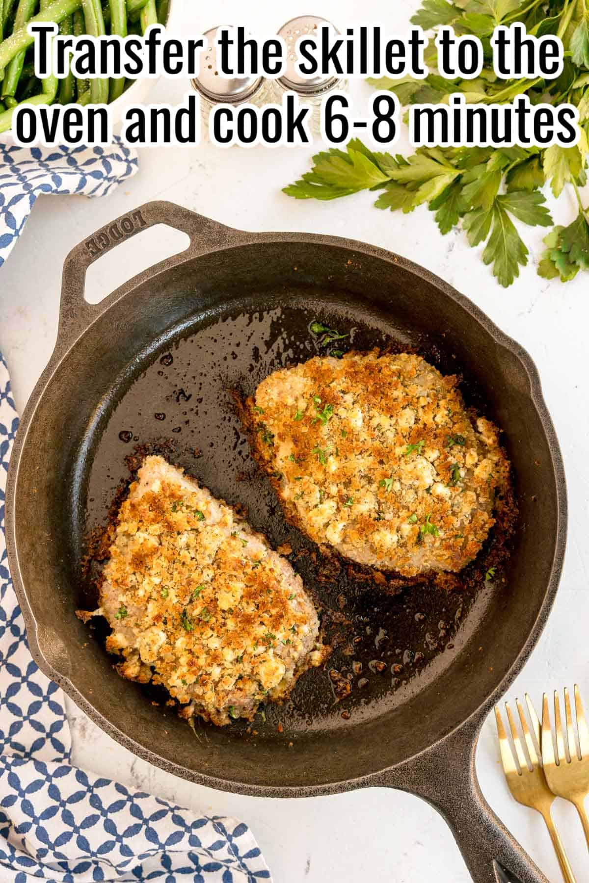 Two browned pork chops in a cast iron skillet. Text on the image says 'Transfer the skillet to the oven and cook 6-8 minutes'.