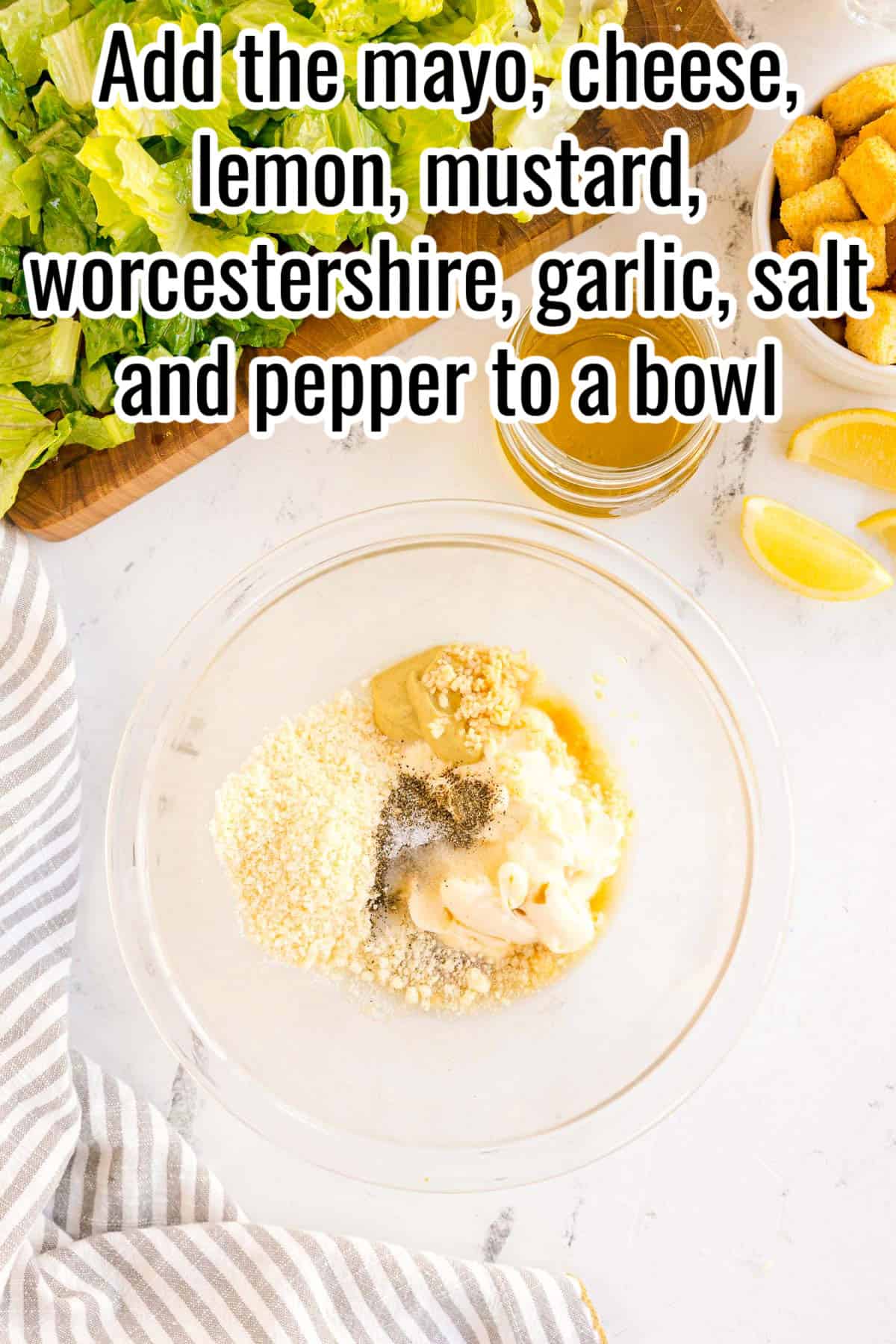 A bowl with mayonnaise, mustard, parmesan, garlic, salt, and pepper. Text on the image says 'Add the mayo, cheese, lemon, mustard, worcestershire, garlic, salt and pepper to a bowl'.