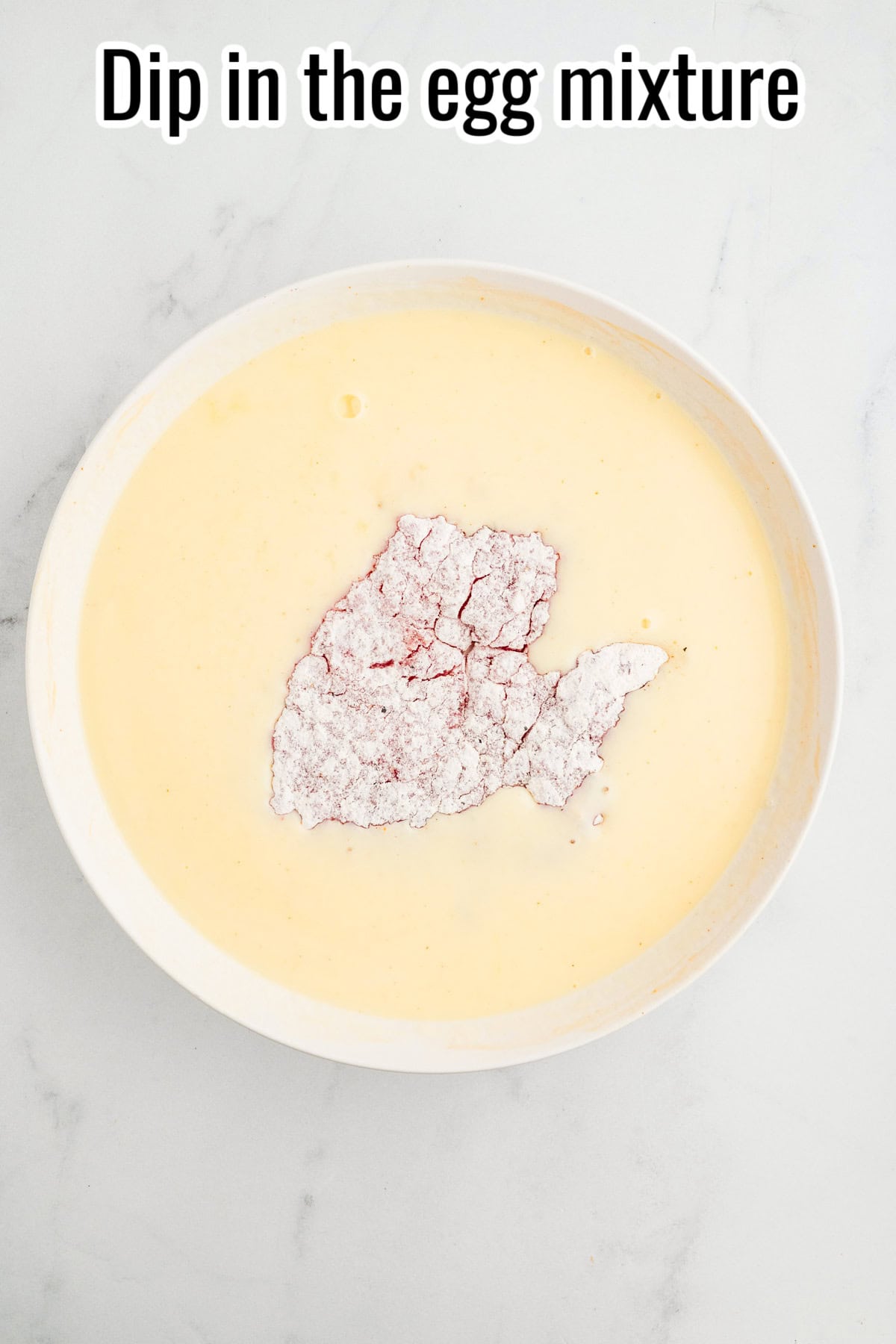 Cube steak in an egg mixture in a shallow bowl. Text on the image says 'Dip in the egg mixture'.
