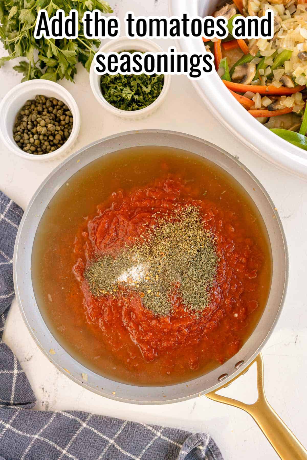 A skillet with tomato sauce and seasonings added to the broth, ready to be mixed, with a text overlay that reads "Add the tomatoes and seasonings."