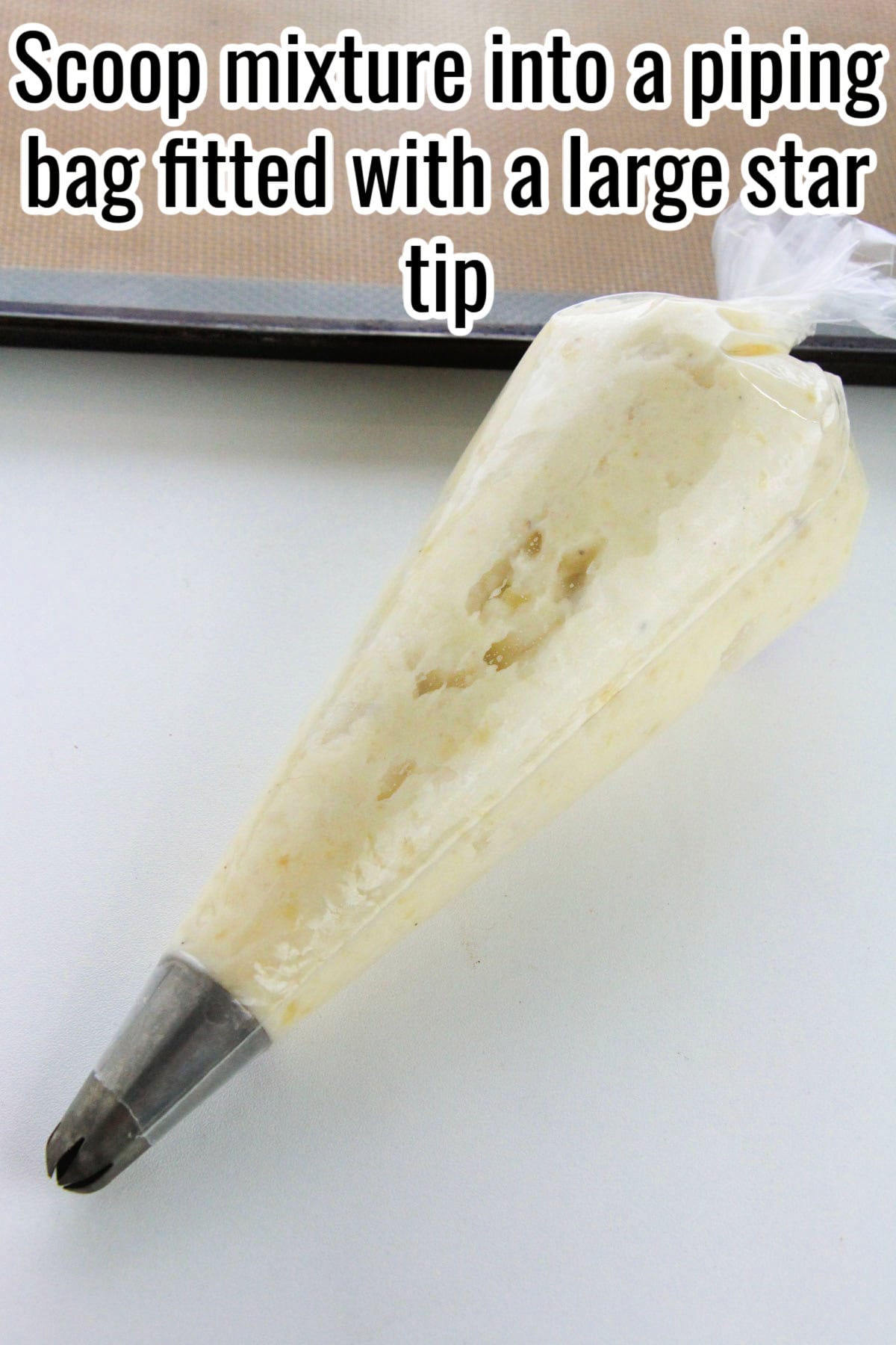 A piping bag filled with mashed potatoes, fitted with a large star tip. Text on the image says 'Scoop mixture into a piping bag fitted with a large star tip'.