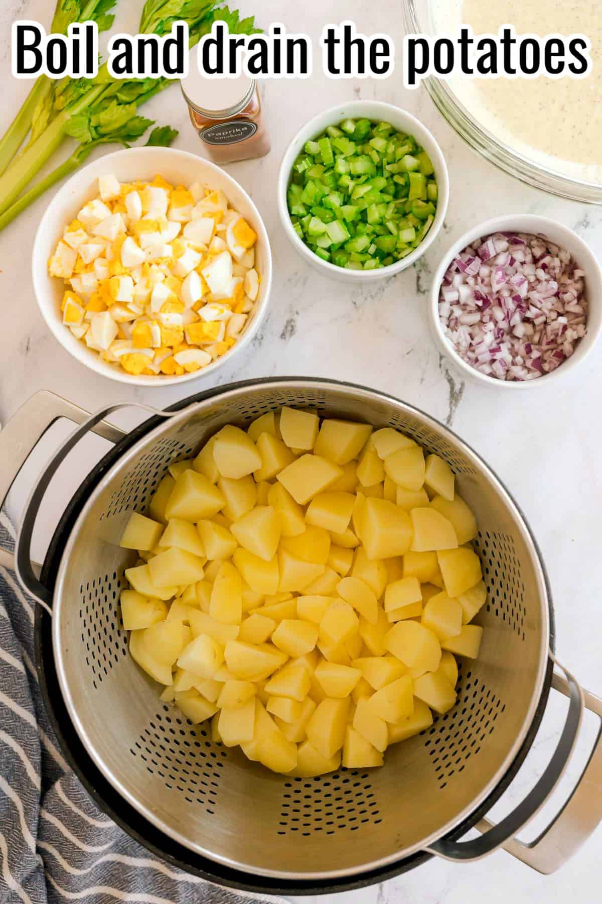 A colander of cooked, cubed potatoes with bowls of chopped eggs, celery, and onion. Text on the image says 'Boil and drain the potatoes'.
