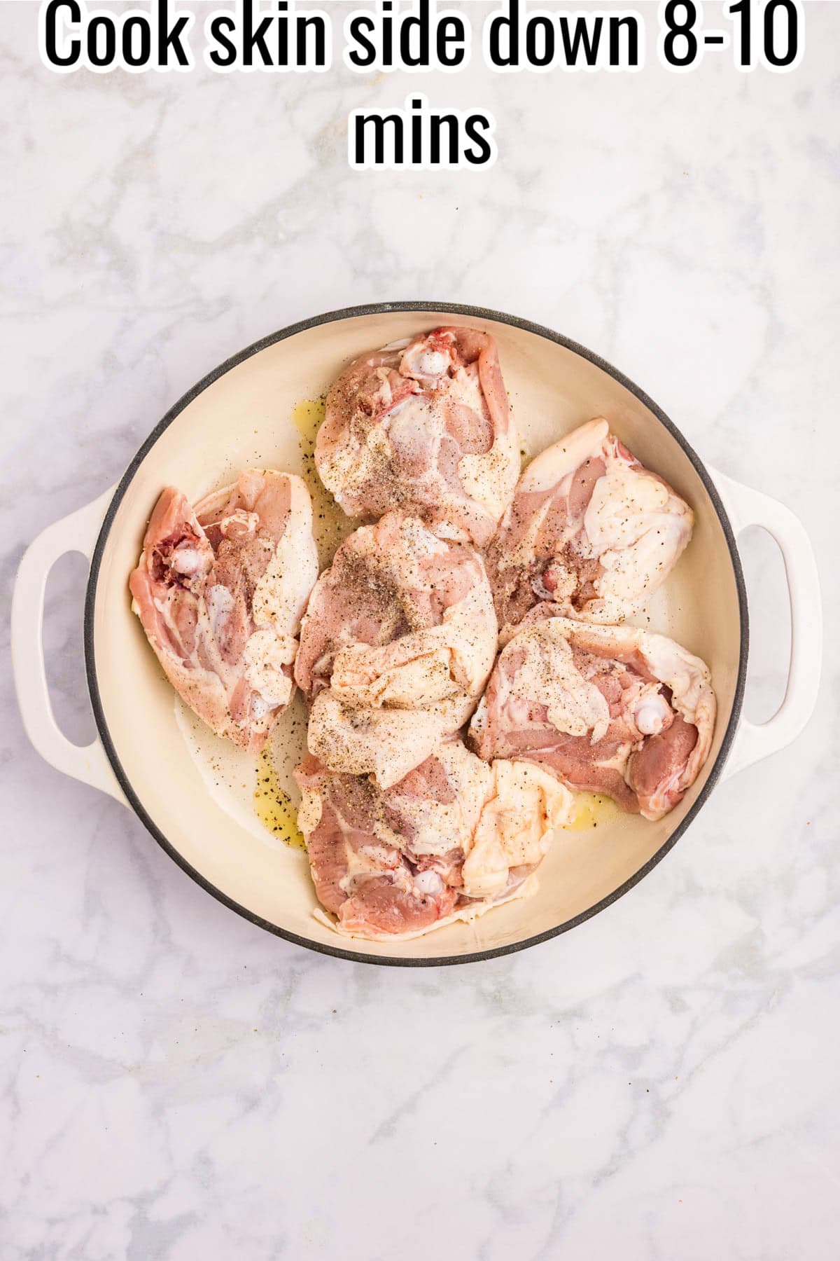Raw chicken thighs cooking skin-side down in a white skillet. Text on the image says 'Cook skin side down 8-10 mins'.