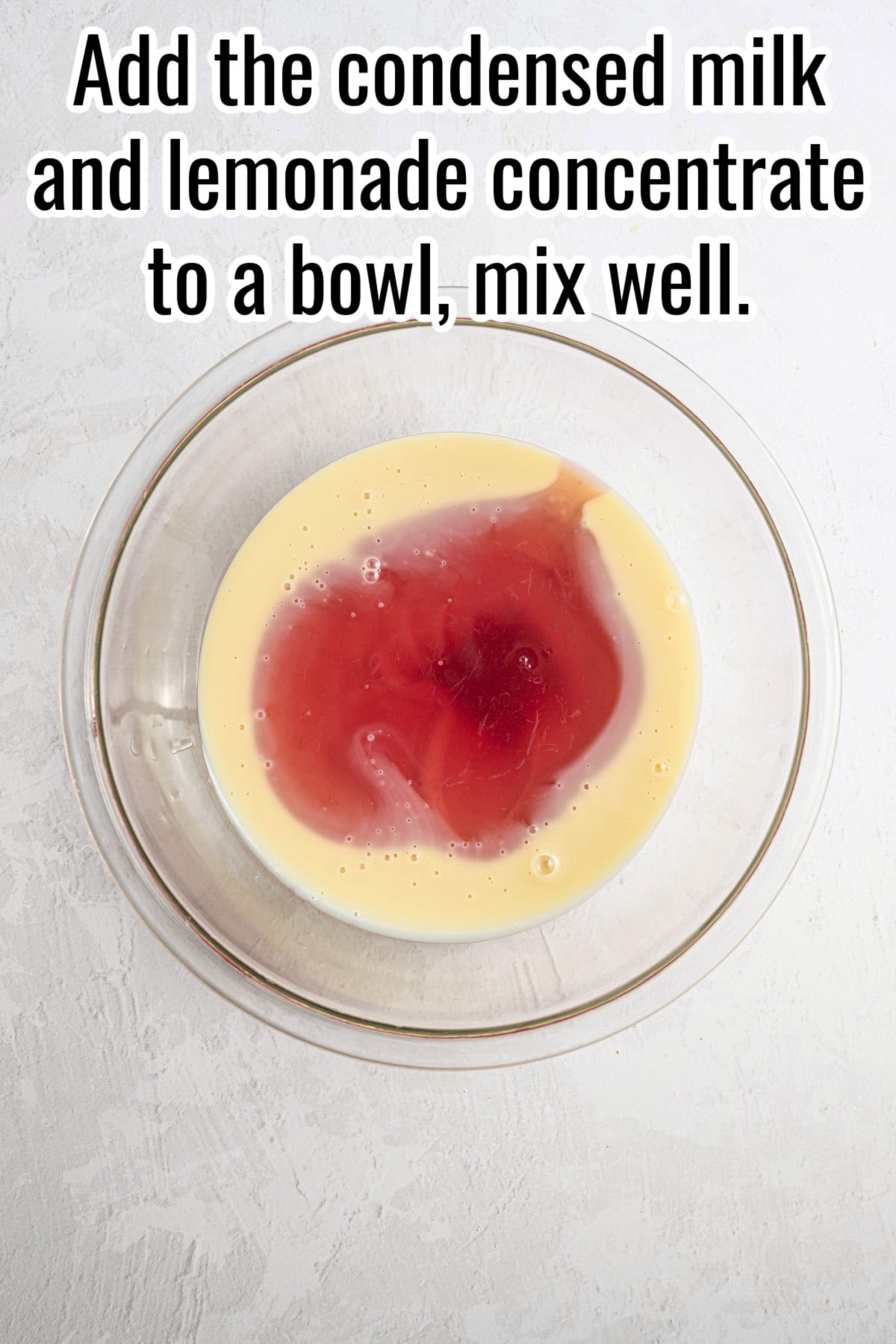 Condensed milk and lemonade concentrate in a glass bowl. Text on the image says 'Add the condensed milk and lemonade concentrate to a bowl, mix well'.