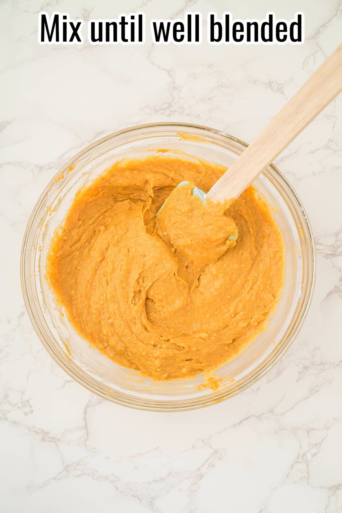 A bowl of smooth pumpkin batter with a spatula. Text on the image says 'Mix until well blended'.