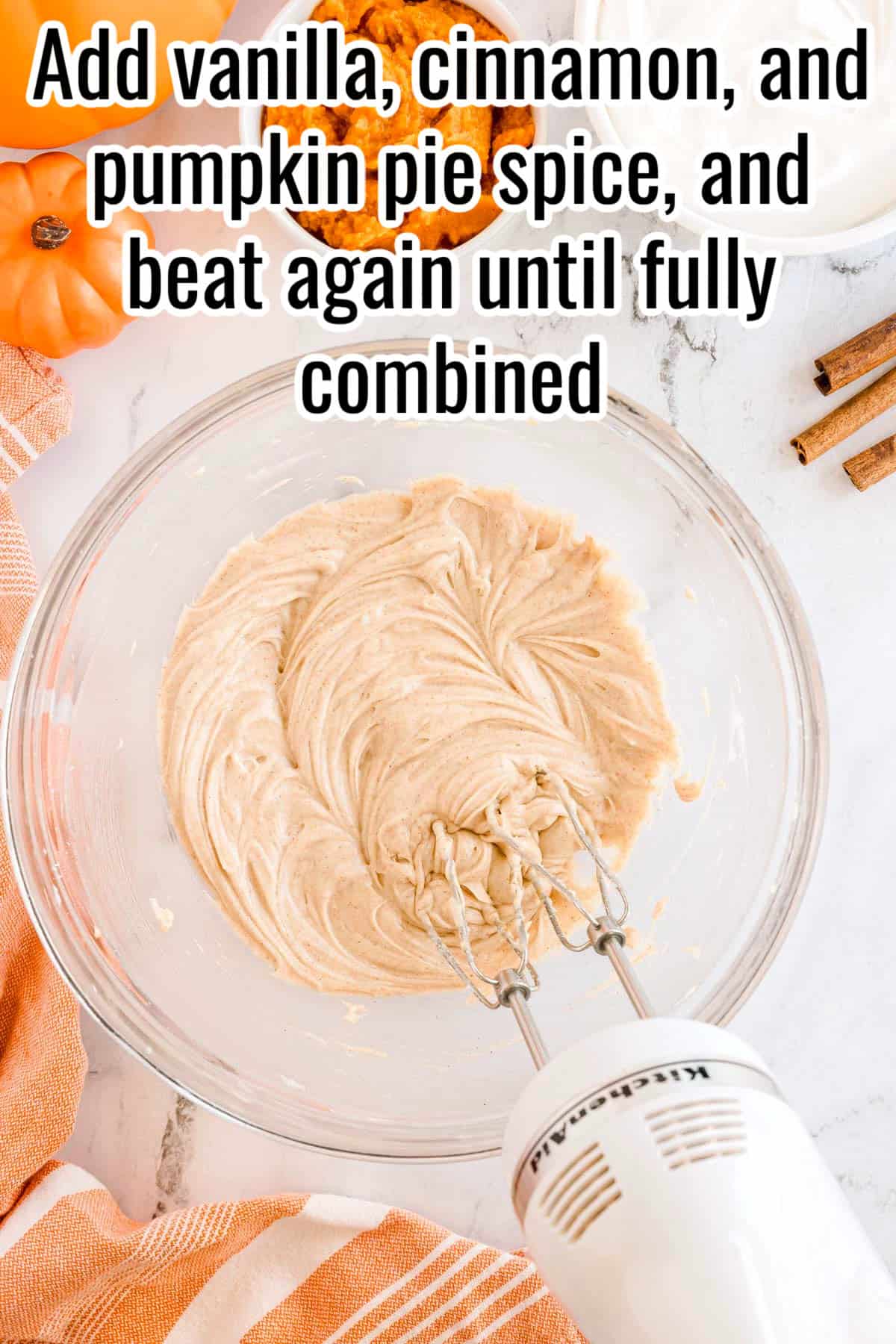 A glass bowl with cream cheese mixture, vanilla, cinnamon, and pumpkin pie spice blended together. Text on the image says 'Add vanilla, cinnamon, and pumpkin pie spice, and beat again until fully combined'.