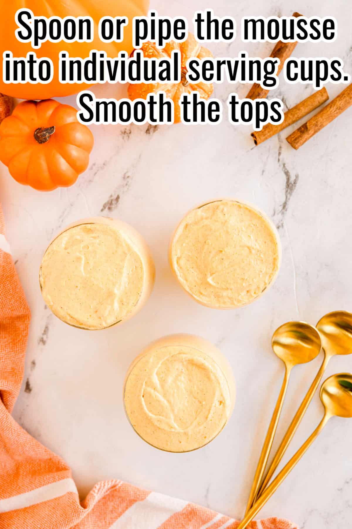 Three cups filled with pumpkin mousse and smoothed on top. Text on the image says 'Spoon or pipe the mousse into individual serving cups. Smooth the tops'.