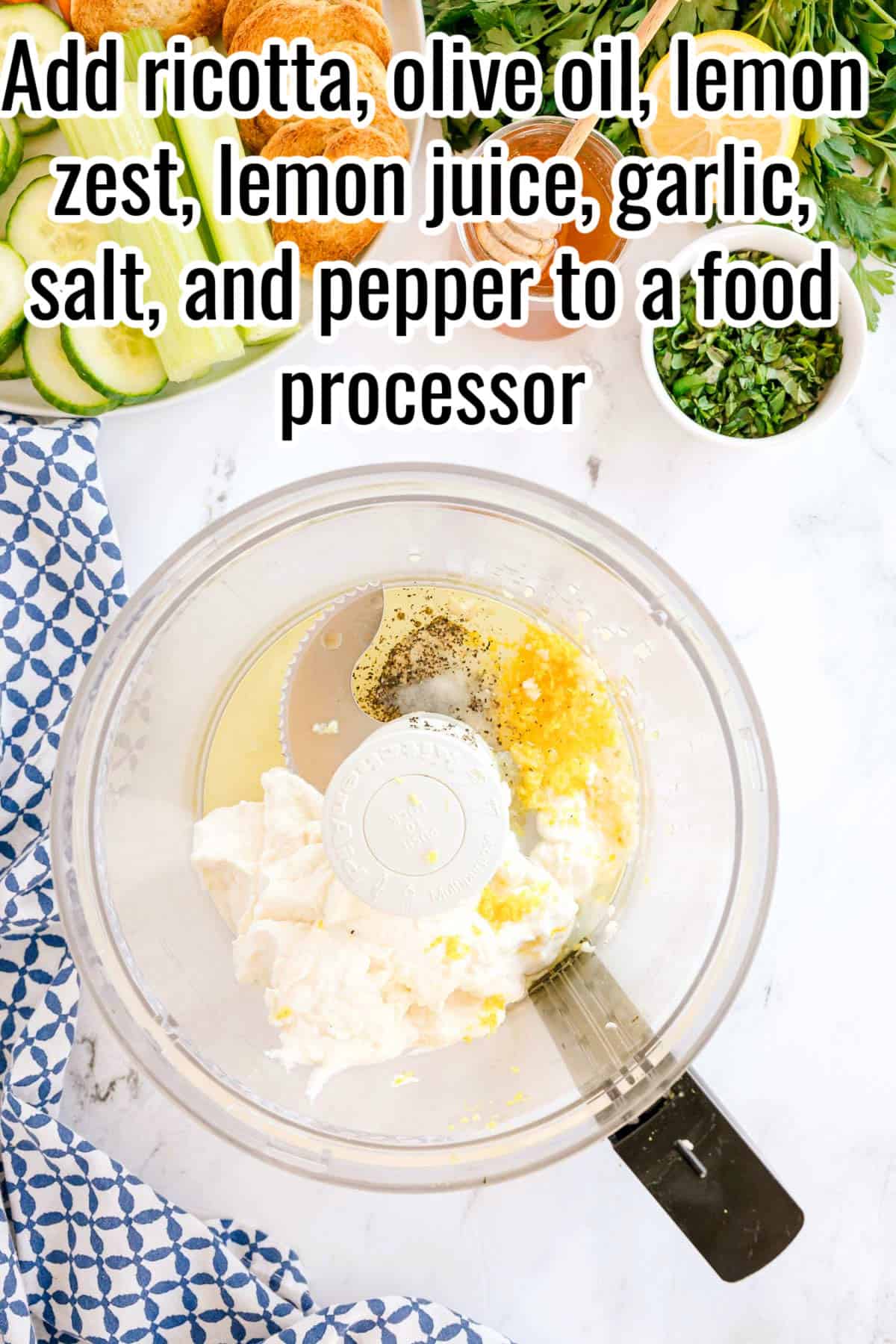 Ingredients in a food processor bowl, including ricotta, olive oil, lemon zest, lemon juice, garlic, salt, and pepper. Text on the image says 'Add ricotta, olive oil, lemon zest, lemon juice, garlic, salt, and pepper to a food processor'.